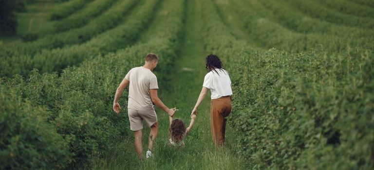 Happy family walking together through a lush green field enjoying nature and togetherness.