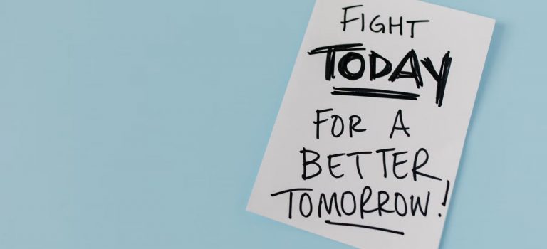Inspirational handwritten message urging action for a better future on paper over a blue backdrop.